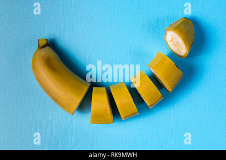 Il minimalismo creativi concetto. Concetto di imprevisti. Appartamento vista laici di banana frutto pattern colorati su sfondo blu. Foto Stock