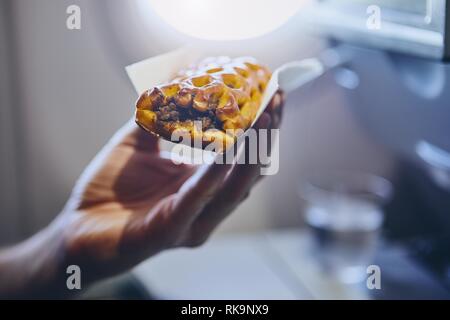 Viaggiare in aereo. Il passeggero gustando uno snack in classe economy durante il volo. Foto Stock
