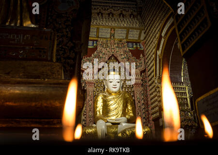 Monywa, Myanmar - 24 Settembre 2016: candele accese di fronte ad una statua di Budda in Thanboddhay Paya tempio principale Foto Stock