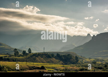 I raggi di luce streak attraverso i bordi frastagliati dell'Anfiteatro montagna nel Drakensberg, Sud Africa Foto Stock