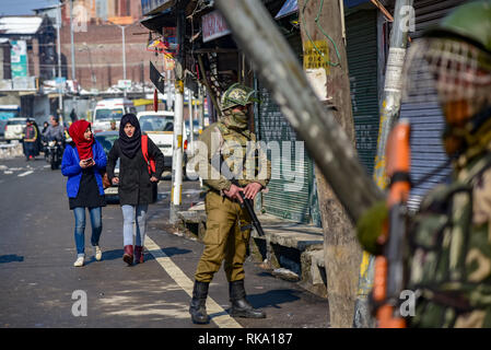 Srinagar, India. 9 Feb 2019. Le ragazze del Kashmir vedere a piedi passato indiano uomo paramilitari di guardia durante le restrizioni in Srinagar. Restrizione alla circolazione dei veicoli sono stati imposti protettivo in parti di Srinagar come gruppi separatisti chiamato per uno sciopero in occasione dell'anniversario della esecuzione di Afzal Guru del Kashmir a chi è stato condannato e dato una condanna a morte per il suo ruolo nel 2001 attentato contro il parlamento indiano. Credito: SOPA Immagini limitata/Alamy Live News Foto Stock