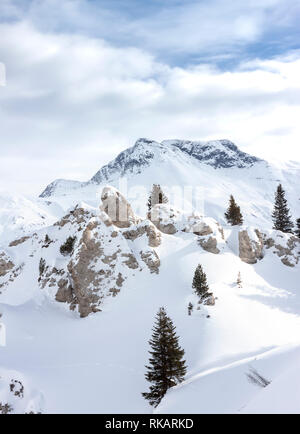 Alpi bellissimo paesaggio di montagna di abeti e rocce sotto la neve Foto Stock