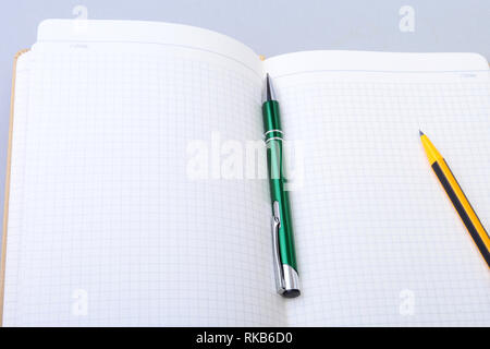 Aprire la pagina vuota notebook e la penna sul tavolo bianco. Foto Stock