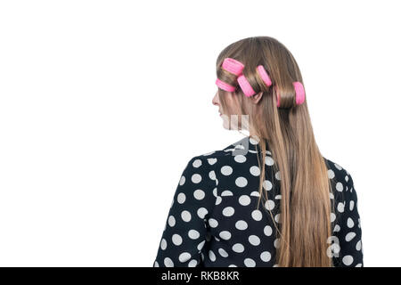 Ritratto di una donna in polka dot shirt con bigodini dal retro, isolato su sfondo bianco Foto Stock