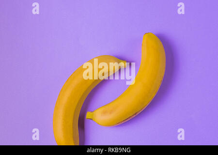 Il minimalismo creativi concetto. Concetto di imprevisti. Appartamento vista laici di banana frutto pattern su colorato sfondo viola. Foto Stock