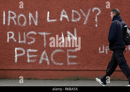 Un pedone passato passeggiate graffiti che recita "signora di ferro? Ruggine in pace" riferendosi all'ex primo ministro britannico Margaret Thatcher nella parte occidentale di Belfast, Irlanda del Nord il 9 aprile, 2013 Un giorno successivo Thatcher della morte. La Gran Bretagna era profondamente divisa sulla eredità dell ex primo ministro Margaret Thatcher come i preparativi per il grand funerale la prossima settimana della donna noto in tutto il mondo come la "signora di ferro". Foto/Paolo McErlane Foto Stock