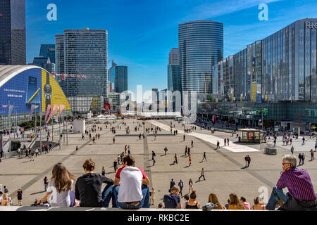 La folla di gente seduta sui gradini di La Grande Arche de la Défense e godersi il caldo sole su di una calda giornata estiva in La Défense ,Parigi,Francia Foto Stock