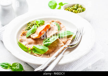 Ravioli di zucca con salsa al pesto in una piastra bianca. Sano cibo vegan concetto. Foto Stock