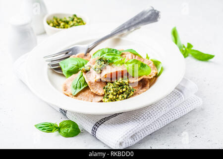 Ravioli di zucca con salsa al pesto in una piastra bianca. Sano cibo vegan concetto. Foto Stock