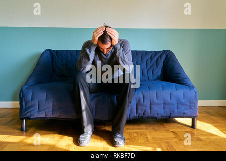 Bel ragazzo in posa - frustrato uomo caucasico preoccupata e ha sottolineato seduto sul divano Foto Stock