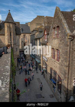 Borgo medievale lane e gli edifici sul Mont St Michel con i turisti il risveglio verso il basso la corsia. Foto Stock