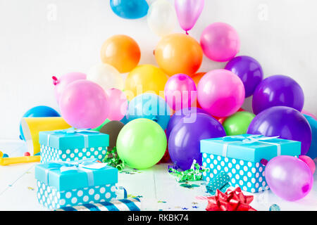 Festa di compleanno palloncini sfondo con decorazione, coriandoli, serpentina, compleanno hat e confezioni regalo su bianco teble in legno Foto Stock