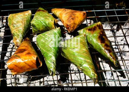 Il nero di riso appiccicoso con il latte di cocco e il Taro, Khao-nieo-ping grigliate di ripieni di riso glutinoso avvolto in foglie di banano Foto Stock