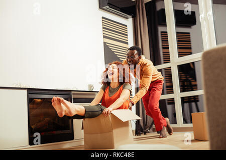 Ridendo afro-americano di marito dirigere la scatola con sua moglie Foto Stock