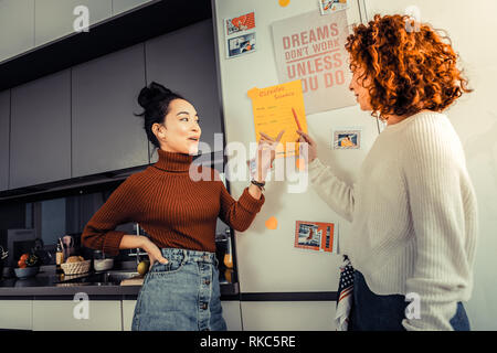 Donna che indossa Gonna Jeans parlando con un amico circa la pulizia Foto Stock