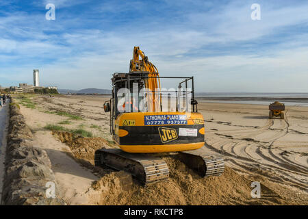 SWANSEA, GALLES - Ottobre 2018: Escavatore e carrello in movimento delle pile di sabbia sulla spiaggia a Swansea dopo venti aveva soffiato al lungomare. Foto Stock