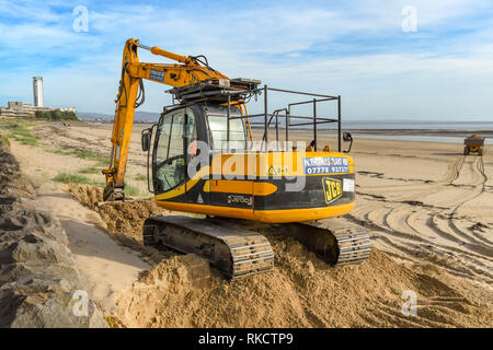 SWANSEA, GALLES - Ottobre 2018: Escavatore e carrello in movimento delle pile di sabbia sulla spiaggia a Swansea dopo venti aveva soffiato al lungomare. Foto Stock