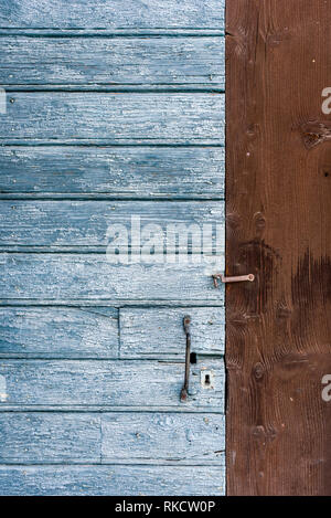 Dettaglio di un tradizionale vernice blu legno porta di ingresso inset marrone in legno pannello parete di alpine dependance con maniglia in metallo e la chiusura a scatto Foto Stock