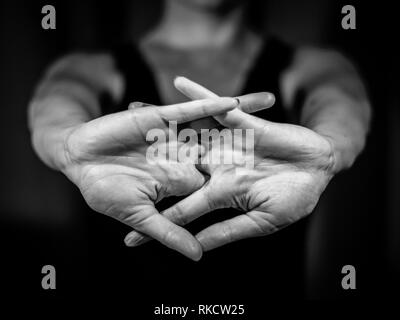 Foto in bianco e nero di giovane donna allungando il suo corpo con le sue mani nella parte anteriore. Knuckles, yoga , sport Foto Stock