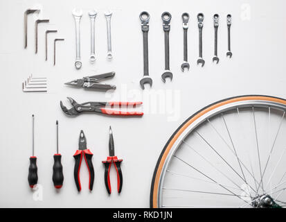 Bicicletta attrezzo di fissaggio kit. Piatto di laici gli strumenti di lavoro e la ruota di bicicletta Foto Stock