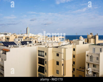 Guardando fuori sui tetti in densamente edificata e popolato di Saint Julians in Malta, sul blu del Mediterraneo con il Casinò inn il mi Foto Stock