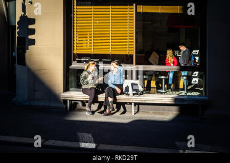 Amici in chat con la luce del sole al di fuori di un cafè sul marciapiede in Oslo Foto Stock