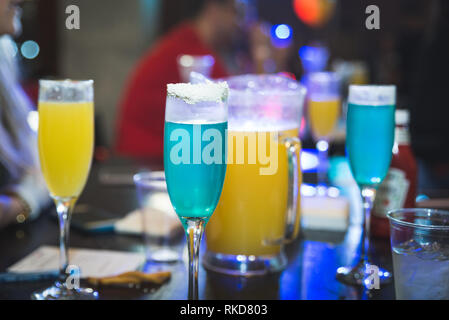 Una Mimosa Brunch su tabelle con blu e arancione di alcol in bicchieri di champagne oe arancione. Il brunch di compleanno, tavola nera. Foto Stock