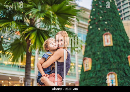 Madre e figlio sullo sfondo di albero di Natale e gli alberi di palma decorata in vacanza tropicale ubicazione. Foto Stock