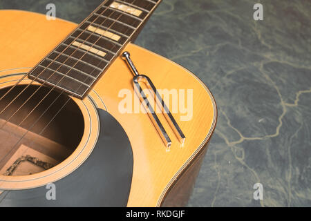 Chitarra acustica su una verde Sfondo marmo, sulla chitarra vi è un diapason, il concetto di musica. Foto Stock