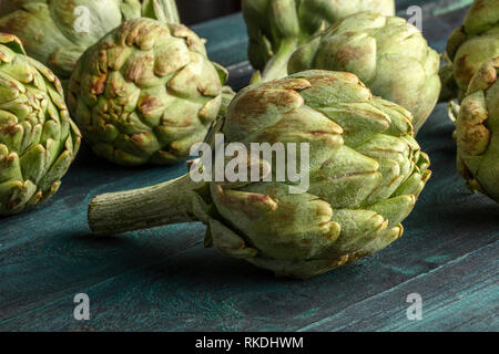 Un primo piano di una di carciofi su un rustico sfondo di legno Foto Stock