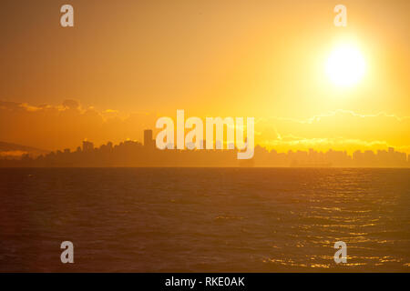 Luminosa mattina presto sole sopra la città di Vancouver skyline come visto da un traghetto in Georgia rettilineo in British Columbia, Canada Foto Stock