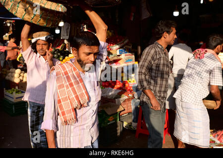 Facchini con i loro cestini a Crawford Mercato del Mahatma Jyotirao Phuke mercato, un commercio all'ingrosso di frutta e verdura in Mumbai, India Foto Stock