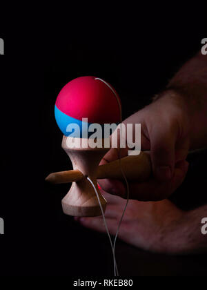 Classico gioco giapponese kendama su sfondo nero. Due ragazzi mani playing kendama Foto Stock