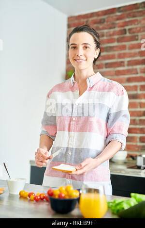 Sorridente giovane donna fare la prima colazione Foto Stock