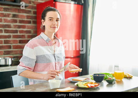 Giovane donna prepara la colazione Foto Stock