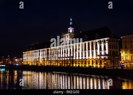 Wroclaw, Polonia - 23 dicembre 2018 - Università di Breslavia edificio principale dal fiume Odra vista notturna Foto Stock