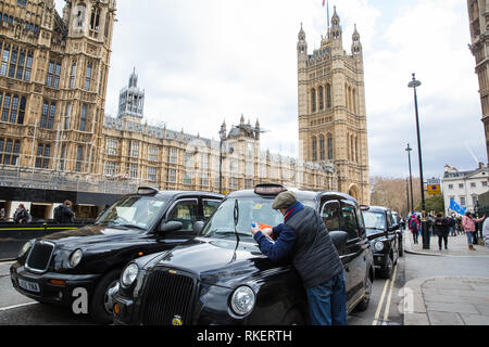 Londra, Regno Unito. Xi Febbraio, 2019. La licenza di taxi driver pulisce il suo veicolo durante un blocco di Piazza del Parlamento e la zona circostante in segno di protesta contro i taxi essendo esclusi dalla Banca Junction, Tottenham Court Road, Tooley Street e le aree di Greenwich, Lewisham, Islington e Hackney. Credito: Mark Kerrison/Alamy Live News Foto Stock