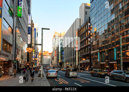 Tokyo, il Ginza. Ora d'oro. Vista lungo la strada con Tiffany store in primo piano. Alberi di Natale sulla strada, il traffico e le persone. Foto Stock