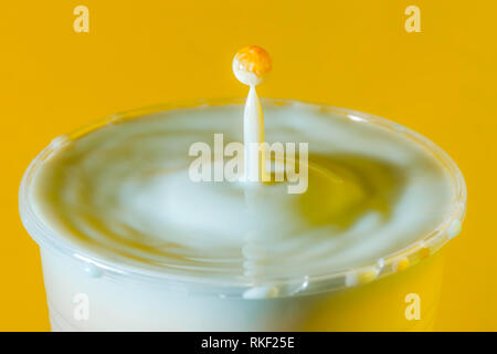 Alta velocità fotografia di una goccia di latte su sfondo giallo in studio Foto Stock