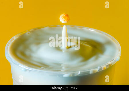 Alta velocità fotografia di una goccia di latte su sfondo giallo in studio Foto Stock