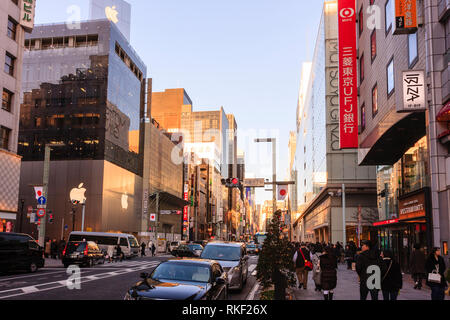 Tokyo, Ginza a ora d'oro. Vista lungo la strada e Matsuya e Apple Store. Marciapiede occupato con gli acquirenti. Illuminata di alberi di natale sul marciapiede. Foto Stock