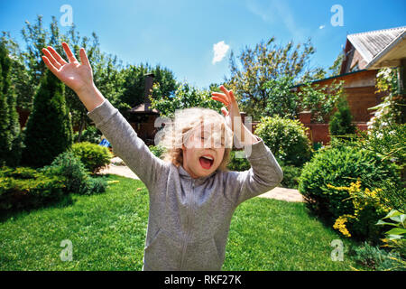 Poco allegra ragazza bionda si diverte sul prato vicino alla sua casa Foto Stock