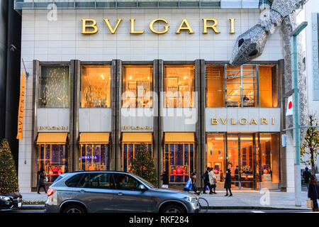 Tokyo, Ginza. Ora blu. Bvlgari store illuminato con telaio di serpente avvolto intorno a. Natale Luce display. Colore di primo piano e persone su strisce pedonali. Foto Stock