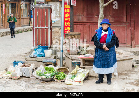 Naxi donna vendita di ortaggi per le strade del villaggio di Baisha, Yunnan, Cina Foto Stock