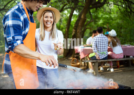 I giovani di sesso maschile e femminile giovane la cottura barbecue in natura Foto Stock