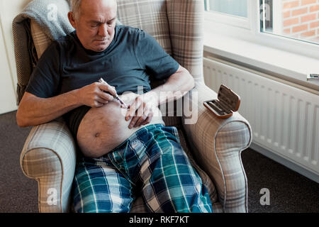 L'uomo anziano con il diabete è l'iniezione di insulina nel ventre a casa. Foto Stock