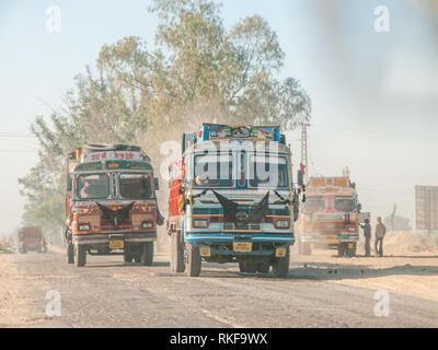 Carrelli colorati su una strada di campagna nel Rajasthan. I camion che trasportano carichi pesanti caratterizzano il traffico in India. Foto Stock