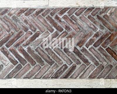 Il vecchio pavimento in mattoni in stile a spina di pesce per lo sfondo, vecchi mattoni marrone pavimento piastrellato con andamento a zig-zag. Foto Stock