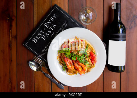 Frutti di mare piccante spaghetti o Spaghetti tom yum con una bottiglia di vino, una fusione di cucina italiana lo stile e il miglior cibo in Thailandia Foto Stock