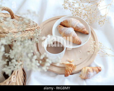 Tazza di caffè con croissant su un vassoio in legno con fiori secchi Foto Stock